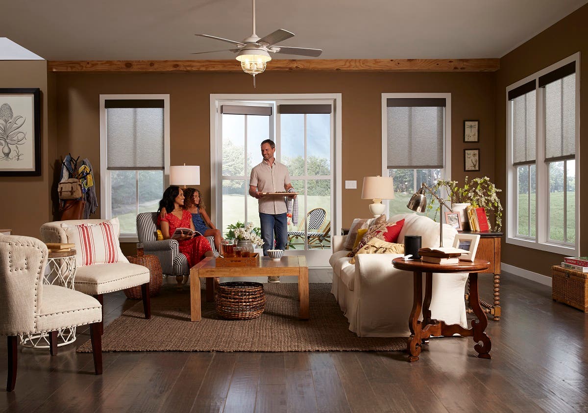 Family of three in living room, enjoying a snack with sheer roller shades closed half way